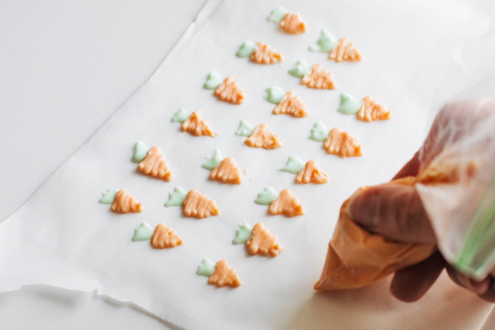 Carrot decorations made from frosting on parchment paper.