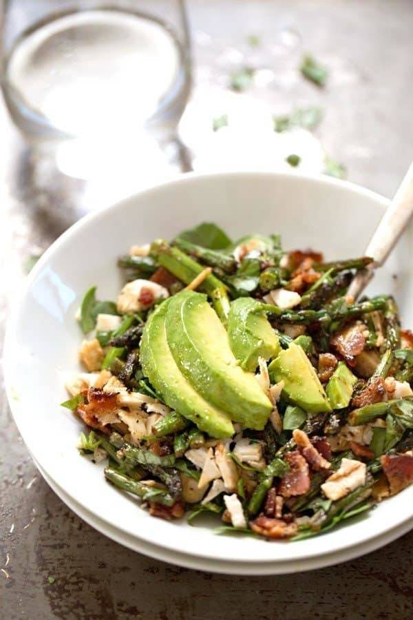 Chicken Bacon Avocado Salad with Roasted Asparagus in a white bowl.