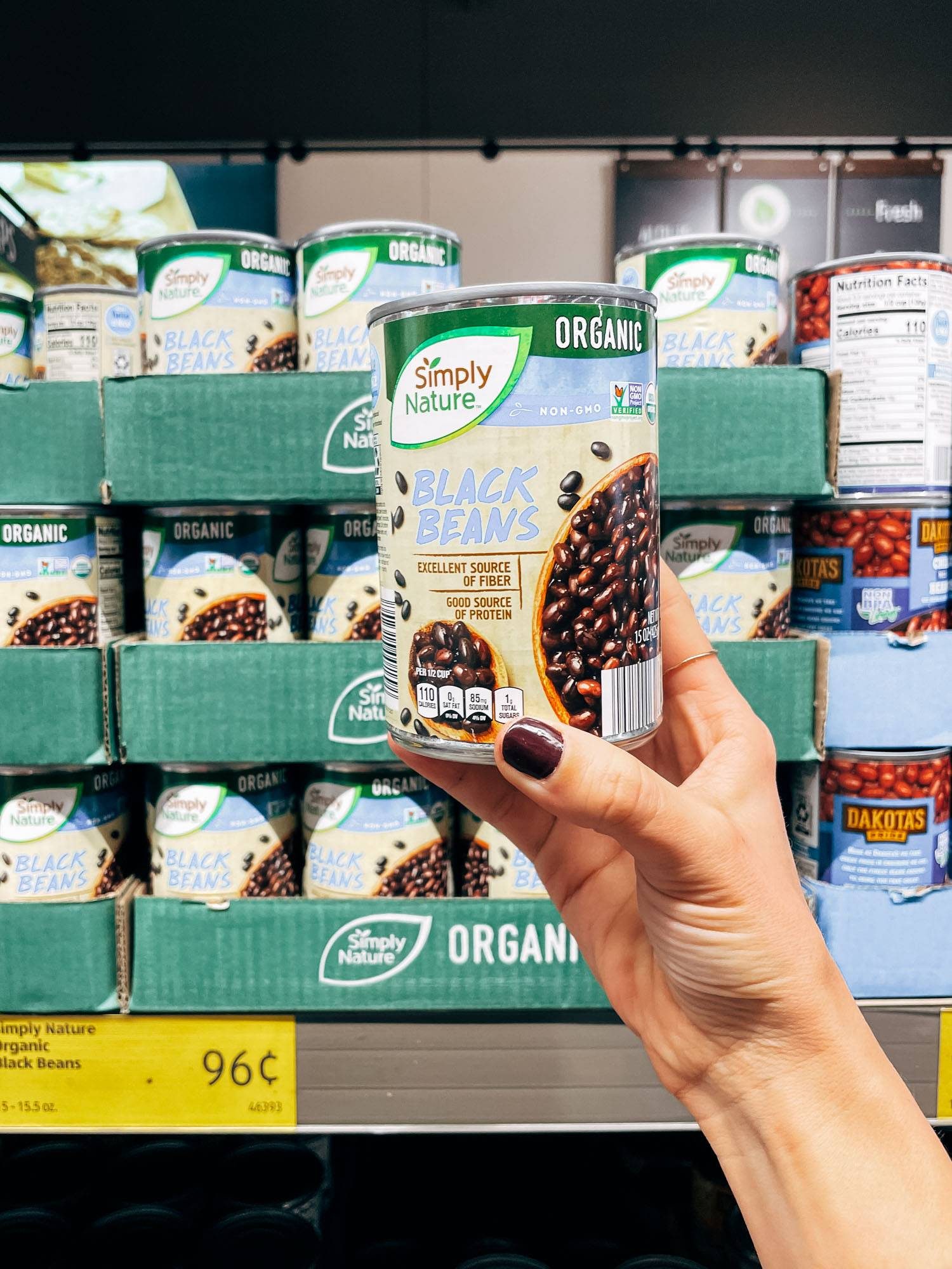 White hand holding a can of black beans