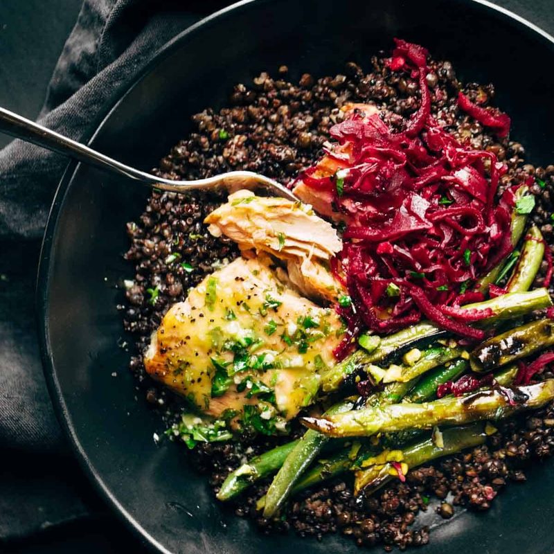 Baked salmon with lentils, green beans, and sauerkraut in bowl.