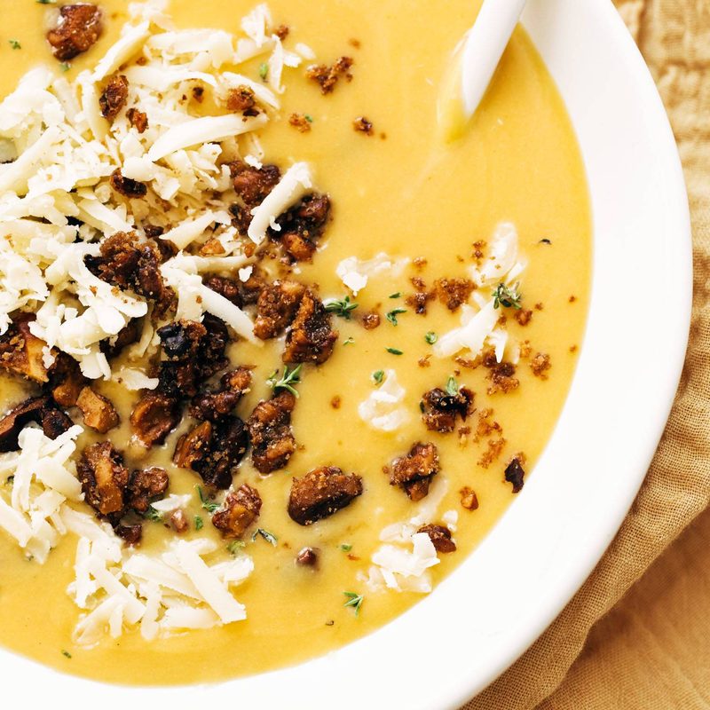 Pumpkin soup in a bowl with walnut crispies and a spoon!